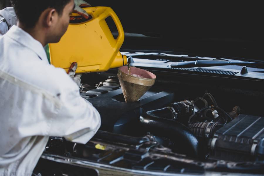 Mecânico realizando troca de óleo de motor em oficina.